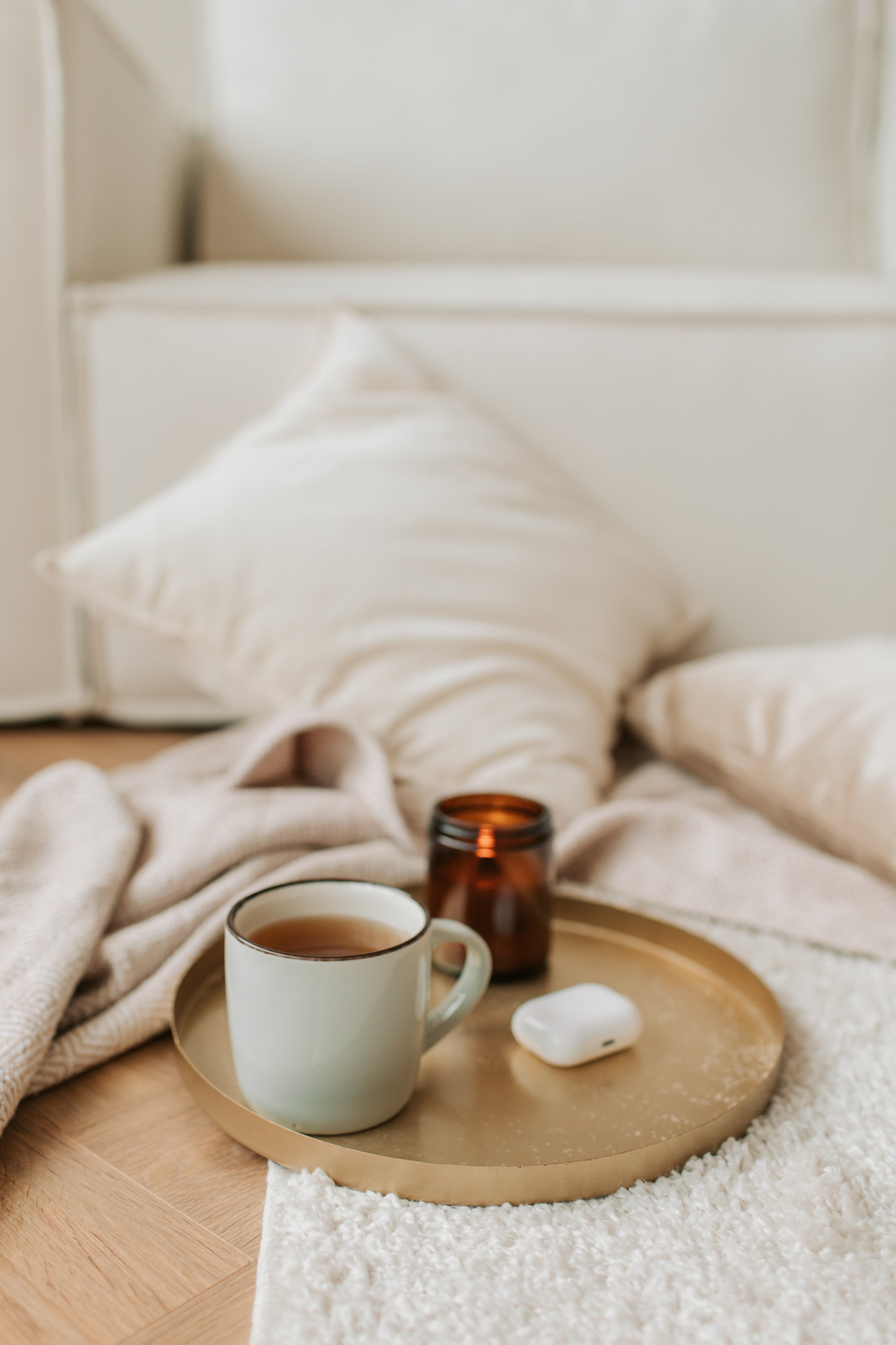 Earphones, Scented Candle and Cup of Tea on Bronze Tray